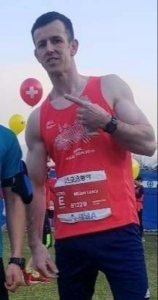 Picture of Bill Leacy wearing a red t-shirt after running a marathon