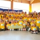 Picture of Cystinosis Ireland DCW and family weekend attendees 2023 holding a sign with 3 million indicating the amount of funding raised for research in 20 years. The group of adults and children are all wearing yellow tshirts